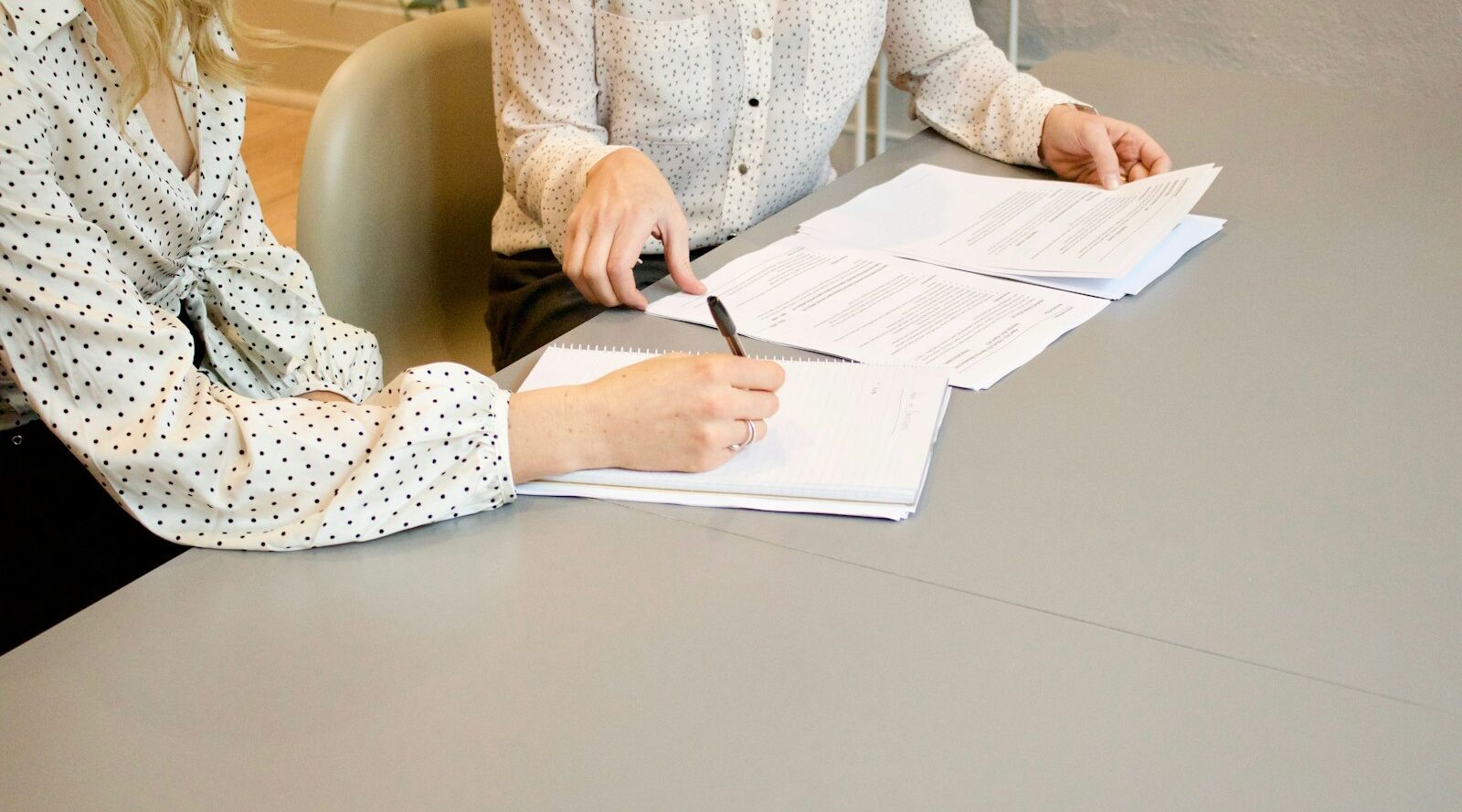 Zwei Personen prüfen Vertragsunterlagen am Tisch – Einstellung einer Pflegedienstleitung