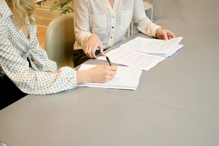Zwei Personen sitzen an einem Tisch und gehen gemeinsam Unterlagen durch